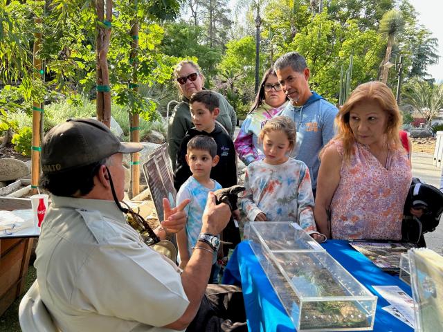 Art Basulto shows a lizard to a group of kids at a fair booth.