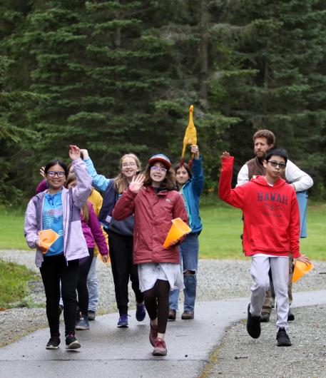 Students walk down an outdoor path waiving their hands in happy success.