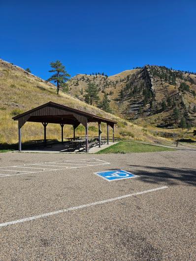 Ramada with picnic tables that can be accessed from the paved surface of the parking area; also, a reserved accessible parking area with direct access to the ramada.