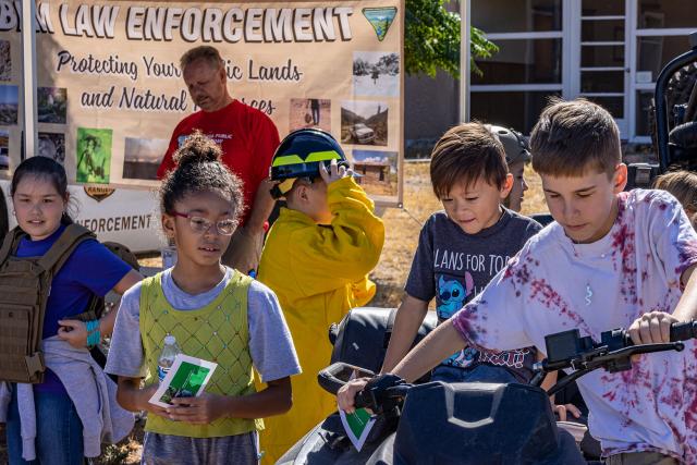 a group of forth grade students try on various gear from law enforcement and fire programs