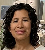 person with shoulder length wavy dark hair smiling for camera