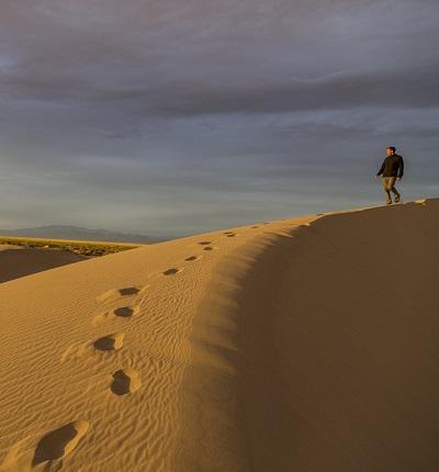 A man walks across a dune ridge.