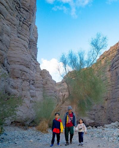A family walks through a tall canyon.