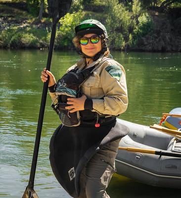 A woman in rafting gear stands with a paddle.