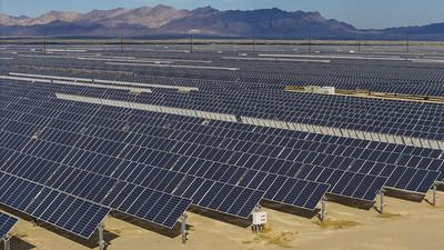 A large solar array in the California Desert with mountains in the background.