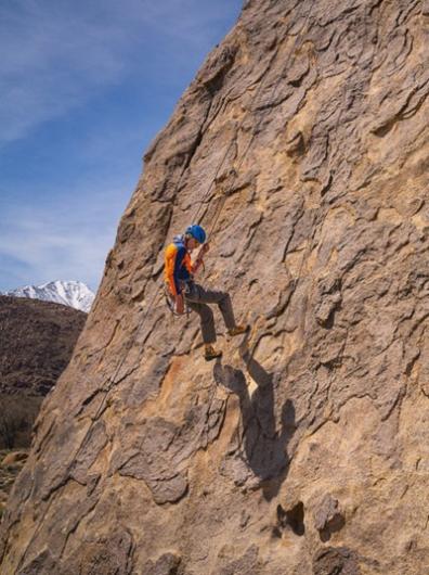 A rock climber repels down a granite face