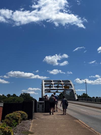 Employees walking on a sidewalk to cross the Edmund Pettus Bridge.