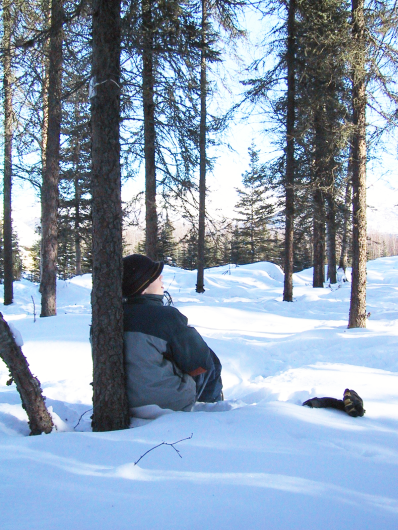 Young student leans against a tree looks at the scenery. 