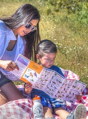 A woman and her child read a guide to the native plants and animals.
