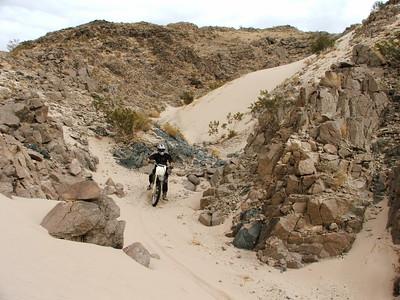 A dirt bike descends  a sandy  hill 