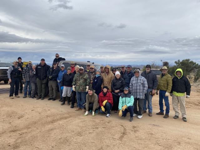 Members, volunteers and agency partners group photo opportunity as they start the clean-up. Approximately 20 people are standing or in the front row on a knee.  