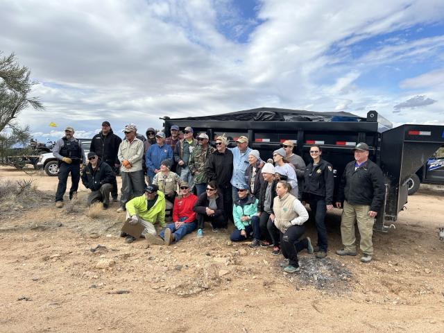 Volunteers and agency partners stand in front of a large dumpster trailer collected 3,780 pounds of garbage.  