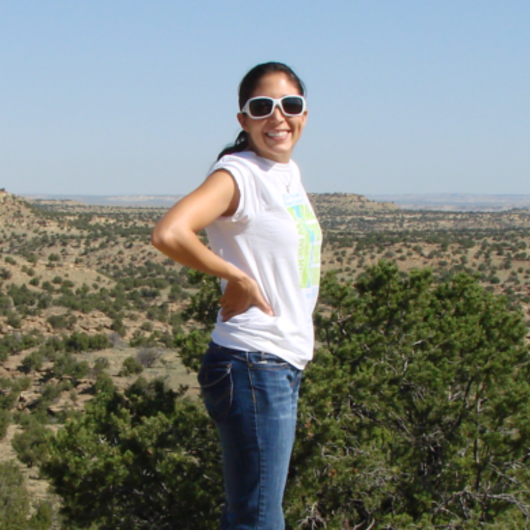 Celina Martinez poses in front of a green landscape.