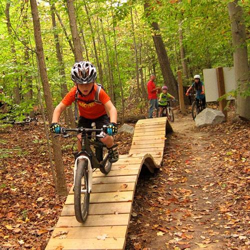 A young boy rides a bike along a wooden, wavy mountain bike path at the Meadowood Special Recreation Management Area in Virginia