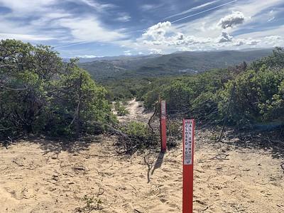 Red carsonite blocking an illegal trail through green chaparral 