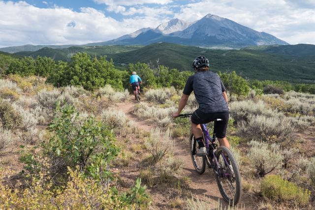 Mountain bikers on a trail overlooking a mountain