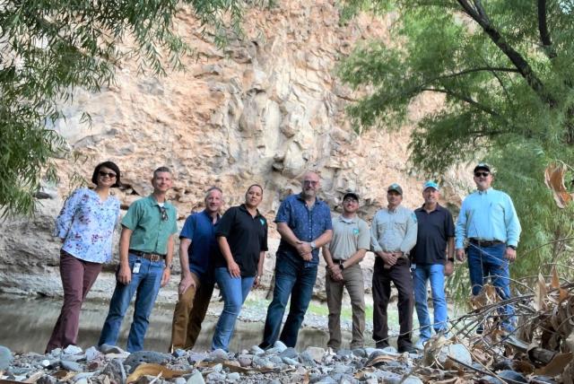 A group of people in front of a cliff face.