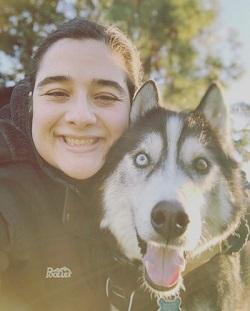 smiling person hugging a husky dog