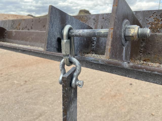 a steel arm hangs from a steel frame by a chain link and horseshoe-shaped clevis attachment
