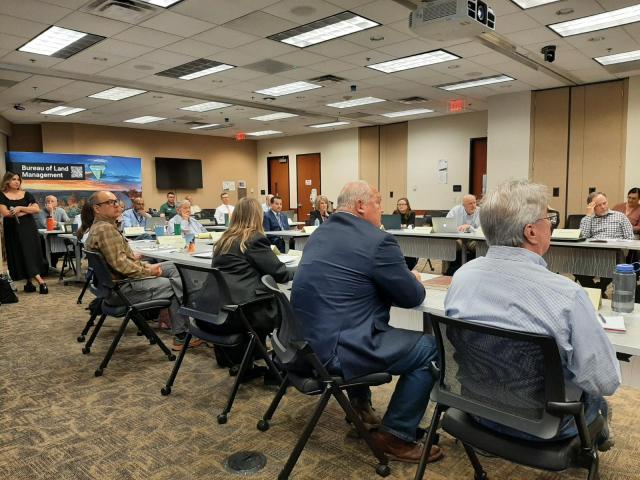 People in a conference room seated around a table. 