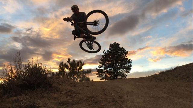 Photo: sihouetted mountain biker goes airborne with sunset in background