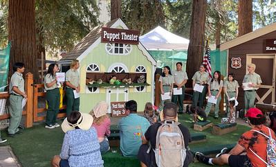 Kids watching a puppet show with uniformed staff nearby