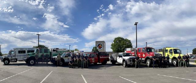 Crews pose in front of seven wildland fire engines from various agencies