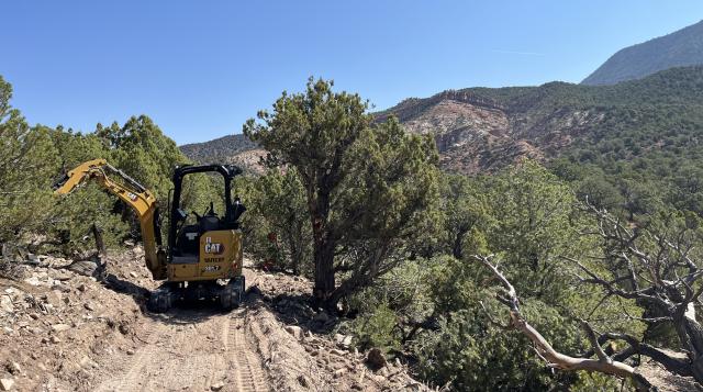 a mini-excavator sits on a trail