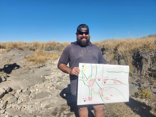 BLM Employee holding a hand-drawn map of a restoration project onsite.