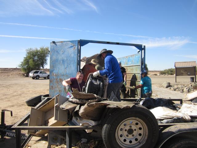 Man on trailer moves trash to dumpster.