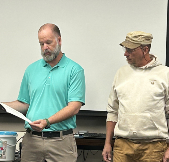 Two men standing in front of group for presentation.
