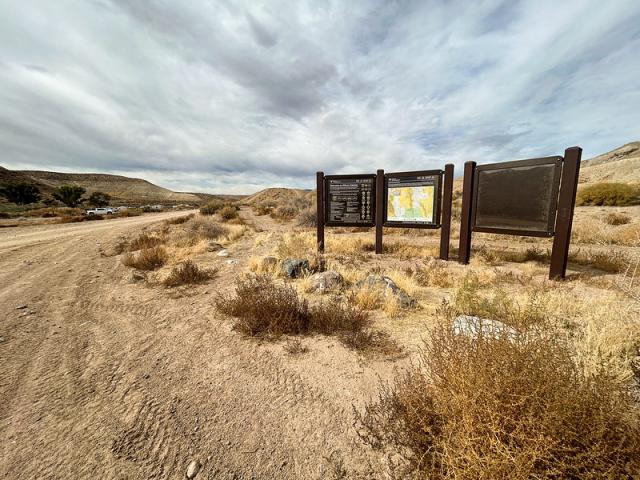 A triple panel of signs on a desert landscape