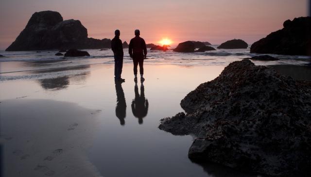 Two men on a beach at sunset