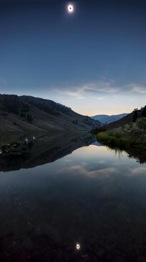 A solar eclipse is reflected in a lake