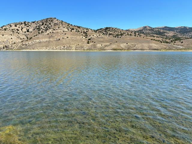 Clear lake with desert hillsides.
