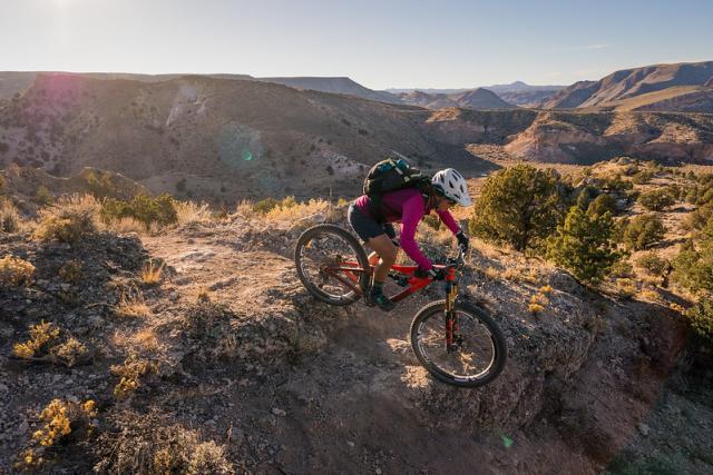 A mountain biker wearing a helmet and backpack on rocky terrain