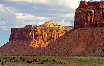 Two buttes towering over grassy area. 