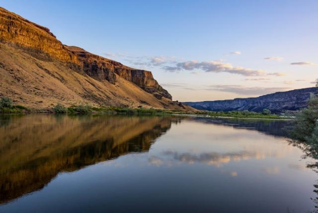 A rock formation relfects on a calm river