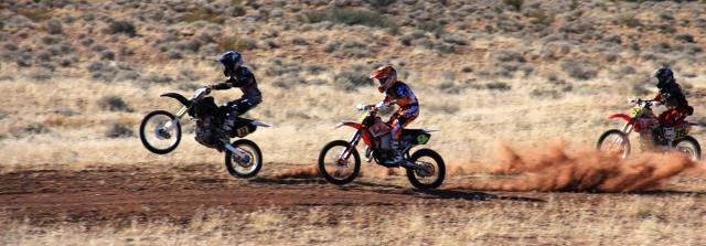 Off-road bike riders drive through the desert