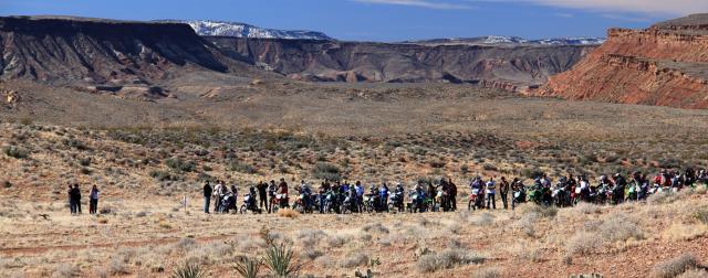 A row of off-road motorcycle riders, lined up at the starting line in the desert