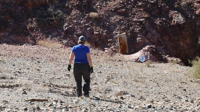 BLM employee walking to trash pile to gather it from the desert.