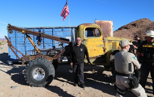 Owner stands in front his large off-road tow truck.