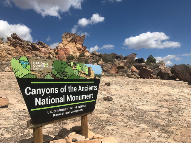 rocky landscape with sky and sign saying Canyon of the Ancients National Monument
