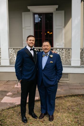 two men pose together for a photo in front of a venue