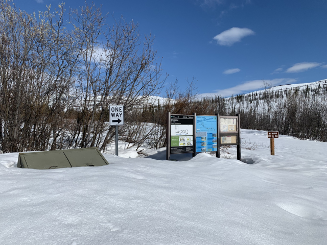 Image of the entrance of the campground with the information panels and trash cans still buried in several feet of snow. 