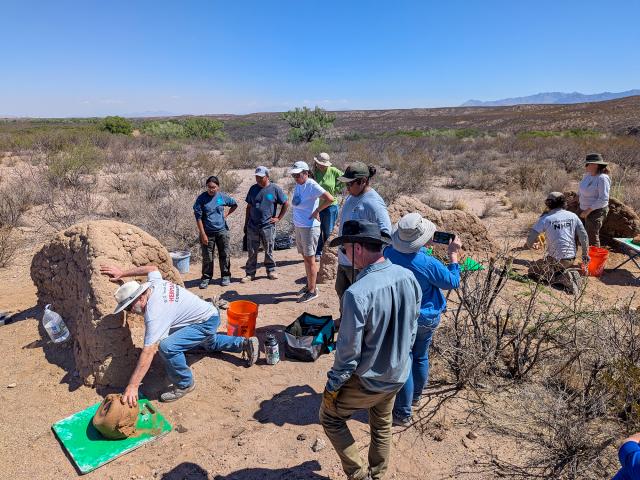 USFS employee Chris Schrager shows the group how to apply mud to the adobe wall. 