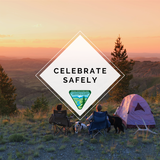 Photo of two people camping at sunset, sitting in two chairs with a dog sitting in between them with a graphic over top saying "Celebrate Safely"