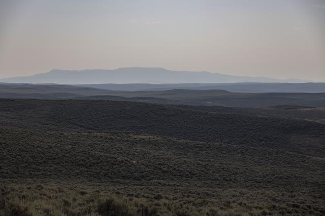 a landscape leading to a mountain faded by haze in the air