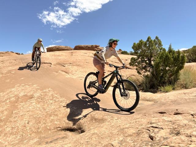 E-bike and mountain biker descend a rolling sandstone hills