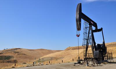 An pump jack in rolling grass fields.
